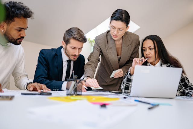 a-group-of-professionals-collaborating-at-a-desk-with-documents-and-a-laptop-in-a-modern-office