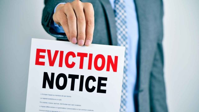 person-in-a-business-suit-holding-up-a-paper-with-the-word-eviction-notice